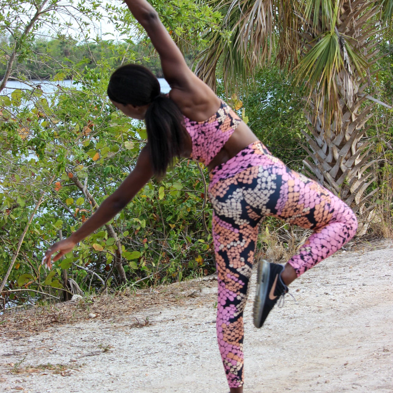 Person in colorful athletic wear posing outdoors with trees and water in the background
